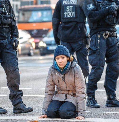 Eine Aktivistin der „Letzten Generation“ sitzt bei Temperaturen um den Gefrierpunkt auf der Straße, auf die sie sich mit einer Hand festgeklebt hatte. Foto dpa