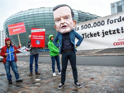 Eine Person mit einer riesigen Maske, die Bundesverkehrsminister Volker Wissing abbilden soll, steht vor einem Plakat mit der Aufschrift „Mehr als 500000 fordern: 29 Euro-Ticket jetzt!“ Foto dpa