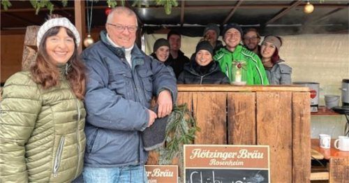 Organisatorin der Dorfweihnacht, Maria Liegl (vorne Mitte hinter dem Tresen) von der KLJB, freut sich zusammen mit ihrer Mannschaft über den regen Zuspruch. Auch Bürgermeister Bernhard Summerer (links mit Frau) fand den Adventsmarkt auf der Obstwiese sehr gelungen. Foto kirchner