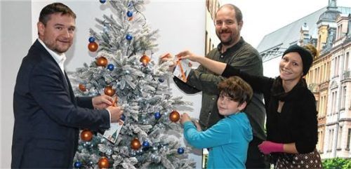 Sie bestücken den Wunschbaum: (von links) Jens Köhler, Raiffeisenbank Rosenheim, Gregor Schumm, Organisator der Aktion, sowie Valentin Arnold und Sarah Wachinger vom Jugendtreff Rosenheim.Foto Schlecker