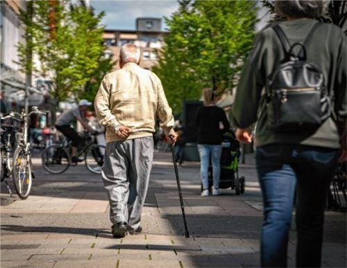 Ein Rentner geht am Stock durch eine Fußgängerzone. Foto dpa