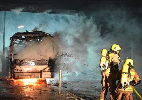 Feuerwehrmänner löschen in Berlin einen Reisebus, der von Unbekannten angezündet wurde. Foto dpa
