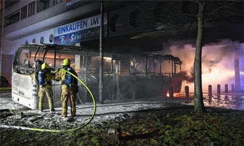 Feuerwehrmänner löschen in der Silvesternacht in Berlin einen Reisebus, der von Unbekannten angezündet worden war. Foto dpa