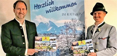 Riederings Bürgermeister Christoph Vodermaier (links) nimmt den Kalender für 2023 von Trachtenvorsitzendem Florian Niedermaier entgegen. Foto Hötzelsperger