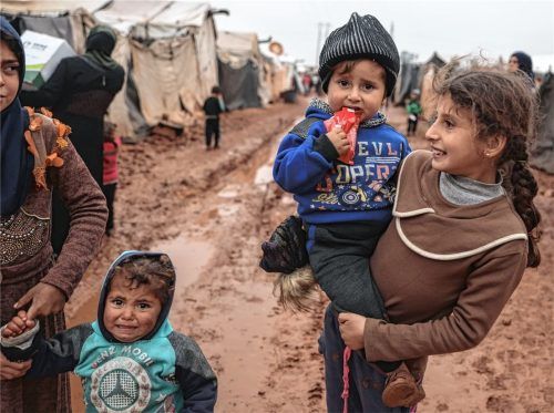 Syrische Kinder warten in einem Flüchtlingslager auf Hilfe, während es regnet. Foto dpa
