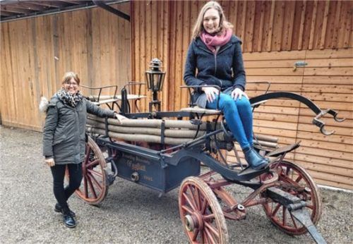 Feuerwehrvorsitzende Lisa Weber (rechts) und Tourist-Info Leiterin Julia Hausmann begutachten die historische Feuerwehrspritze aus dem Jahr 1903. Foto re