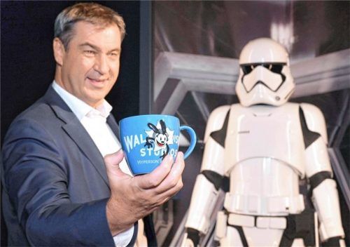 Der bayerische Ministerpräsident Markus Söder (CSU) steht mit einer Disney-Tasse im Rahmen der Ausstellung „Disney 100“ in der Kleinen Olympiahalle vor einer Figur aus „Krieg der Sterne“. Foto dpa