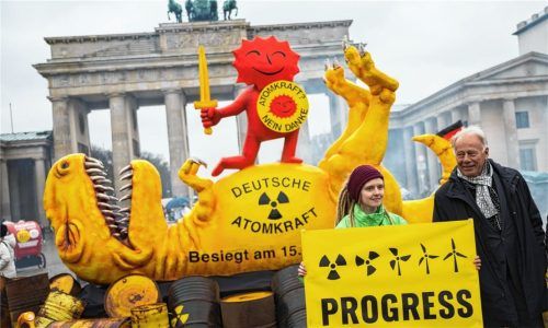 Jürgen Trittin (Bündnis 90/Die Grünen), Mitglied des Deutschen Bundestages und ehemaliger Umweltminister, steht neben einer Aktivistin vor einer Dinosaurier-Figur und der roten Sonne, Teil des Anti-Atomkraft-Logos, bei einer Aktion der Umweltorganisation Greenpeace vor dem Brandenburger Tor.Foto dpa