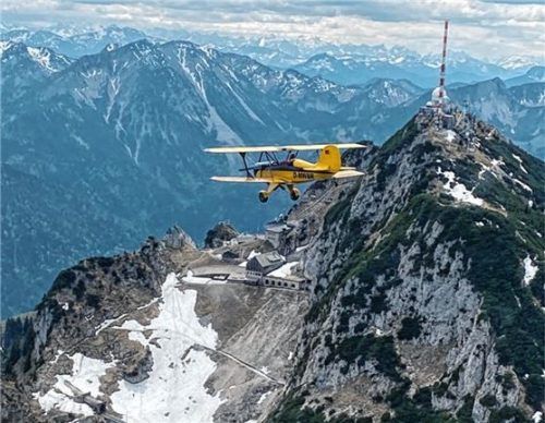Der gelbe Doppeldecker vor dem Wendelsteingipfel erinnert an den Film „Die tollkühnen Männer in ihren fliegenden Kisten“.Foto Florian Becker