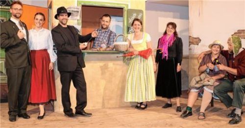 Beim Standl-Hans von „Niederhinterbergkirchenthalhausen“ treffen sich (von links) Bürgermeister Flitzmeier (Markus Aicher), Mona (Marleen Graf) und Giacomo da Capo (Moritz Hecker), Standl-Hans (Florian Thalhammer), Ursl Summwiesler (Alexandra Frank) und Brunhilde Bremsbichler (Gitti Pelzl) sowie Schranken-Susi (Kathi Steiner) und der Weichen-Wastl (Wolfgang Grill). Foto Rehberg