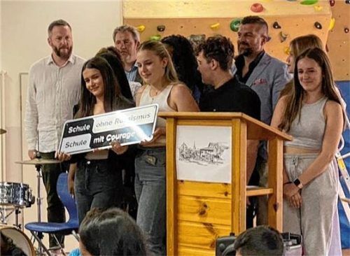 Die Schildübergabe mit (von links, hinten) Patenvertreter Christian Hlatky, Rektor Michael Holzner, Schulamtsdirektor Herbert Unterreiner sowie (von links, vorne) Schülersprecherinnen Erina Fazlija und Emma Stojanovic und Schüler der SMV Petrit Beqiri und Ruzhana Kavroshilova.