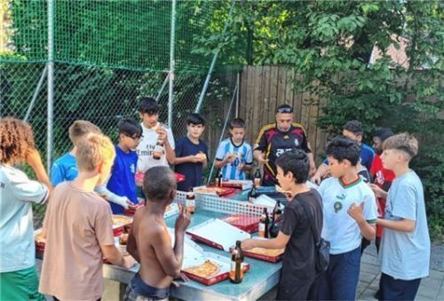 Pizza-Essen nach getaner Arbeit: Die Kinder der Endorfer Au und Fußballtrainer Özgür Yildirim. Foto Privat