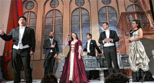 Alfredo (links: Juhyuk Kim) stimmt sein Trinklied an, während Violetta (Mitte: Selin Dagyaran) noch skeptisch ist.Foto janka