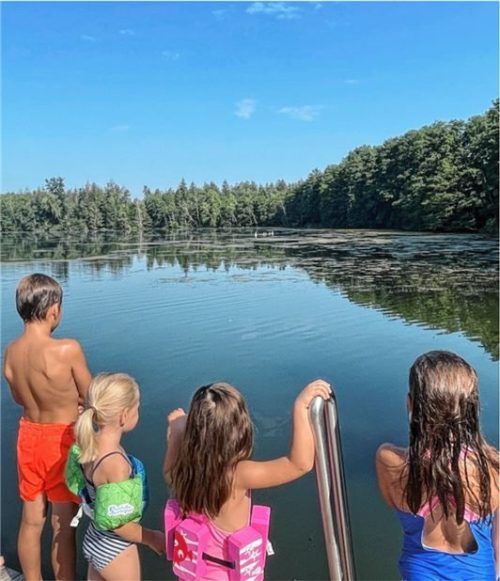 Badefreuden trotz Bewuchses. Jugendliche pflücken in Eigeninitiative auf SUP-Brettern die Pflanzen ab.