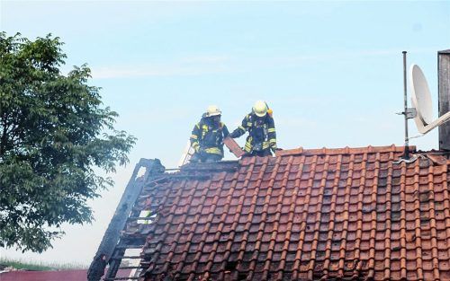 Feuer unterm Dach: Zwei Wehrler sind auf dem Wohnhaus zugange. Der Brand des Stadels am Samerberg hatte auch das angrenzende Gebäude in Mitleidenschaft gezogen. Foto Reisner