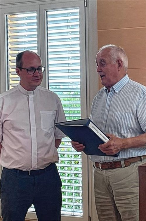 Franz Burghardt (rechts) überreicht Pfarrer Andreas Przybylski das Findbuch.