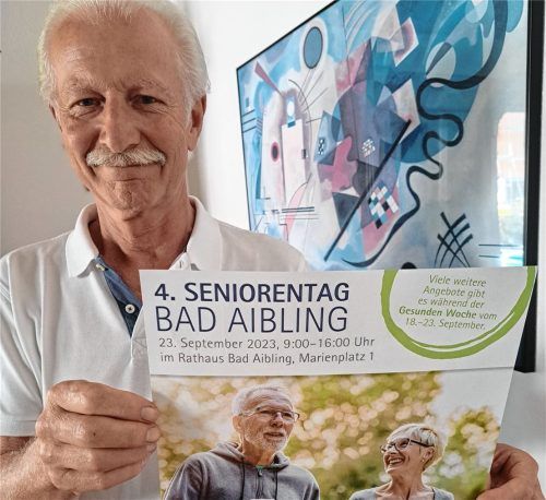 Seniorenbeauftragter Dieter Bräunlich zeigt das Plakat, mit dem für den Seniorentag in Bad Aibling geworben wird. Foto  Hadersbeck