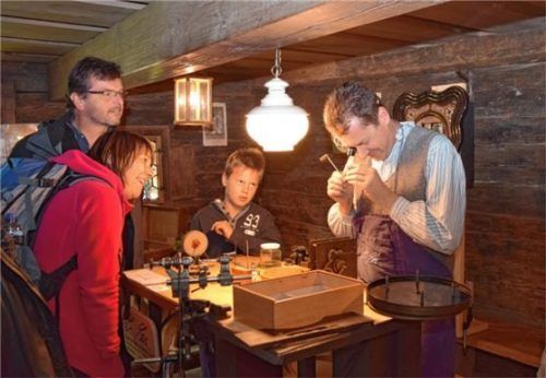 Der Uhrmachermeister Christian Schmeller repariert in der Stube des Holzmannhofes historische Zeitmessgeräte. Foto Bezirk Oberbayern, Bauernhausmuseum Amerang