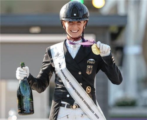 Freude über EM-Gold: Jessica von Bredow-Werndl steht mit ihrer Goldmedaille und einer Champagnerflasche bei der Siegerehrung.Foto dpa/Friso Gentsch