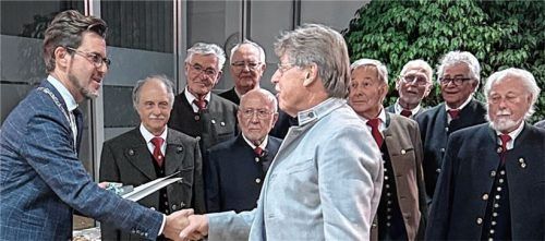 Bürgermeister Karl Mair (links) überreicht Dr. Andreas Daxer die Bürgermedaille der Gemeinde Stephanskirchen. Im Hintergrund Mitglieder des Männergesangvereins. Foto Patscheider