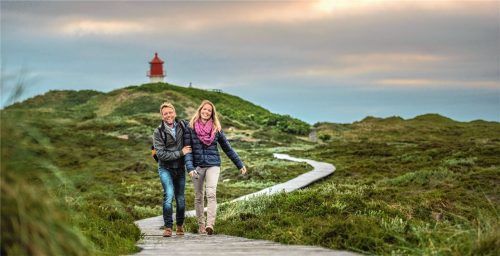 Der neu gebaute Bohlenweg führt hinauf zum „kleinen Leuchtturm“, dem Quermarkenfeuer Norddorf. Der markante rot-weiße Turm steht mit seinem Sockel auf einer Düne am östlichen Rand des Kniepsandes und bietet einen herrlichen Rundblick über die Insel. Foto DJD/AmrumTouristik/Oliver Franke