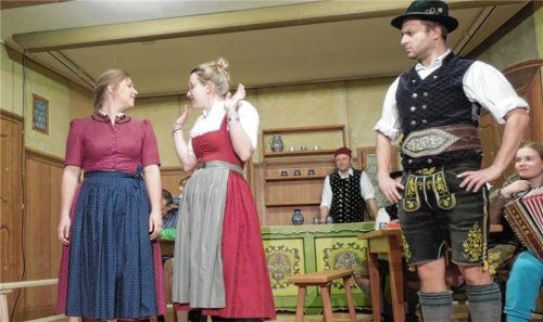 Wirtstochter Hanni (Vroni Altendorfer, von links) im Zwiegespräch mit ihrer Liebschaft-Rivalin, der „trutzigen Lies“ (Katharina Schildhauer). Weiberheld Martl Wegrainer (Georg Schildhauer) schaut diesem Treiben misstrauisch zu. Im Hintergrund verfolgt der Wirt (Martin Hainzl) die Szene.Foto re