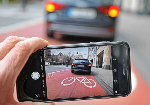 Ein Mann hält mit seinem Smartphone ein Parkvergehen als Bild fest (Symbolfoto). Der selbst ernannte Anzeigenhauptmeister Niclas M. (18) aus Sachsen-Anhalt hat nach eigenen Angaben im Jahr 2023 mehr als 4000 derartige Ordnungswidrigkeiten zur Anzeige gebracht. Foto dpa/Oliver Berg