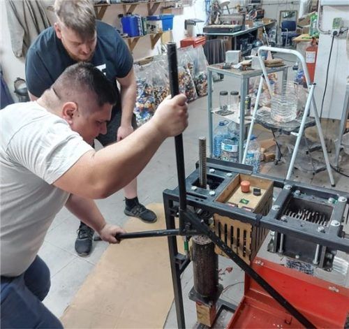 Holger Reiter und Alexander Plettl bei der Herstellung eines neuen Kunststoffteils aus geschredderten Flaschendeckeln. Der Kunststoff wird in der Maschine erhitzt und dann in eine Form gepresst. Daraus lassen sich zum Beispiel Becher oder Kreisel herstellen.Foto re