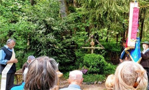 Diakon Simon Frank (links) betet vor dem „Fliegerkreuz“ (Mitte) mit den Anwesenden für den Frieden in der Welt und bat die Gottesmutter um ihre Fürsprache bei Gott. Der Soldatenverein Rott wurde durch die Fahnenabordnung (rechts) repräsentiert. Foto stelzer