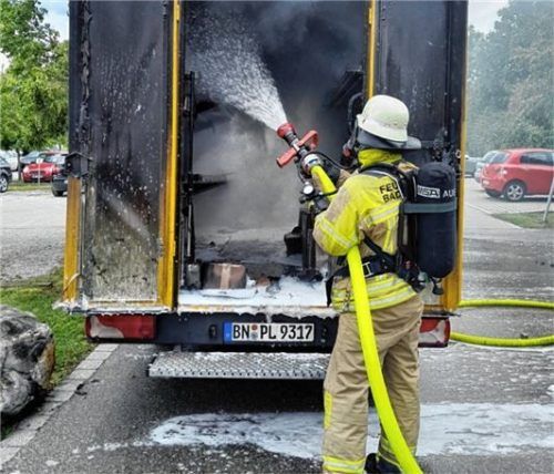 Ein Mitglied der Feuerwehr Bad Aibling bekämpft die Flammen über die Ladeklappe am Heck des Fahrzeugs.