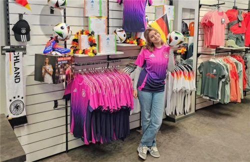 Azubi Jusaj Adiana bei Intersport stellt die EM-Fanartikel in ihrem Laden vor. Foto Intersport