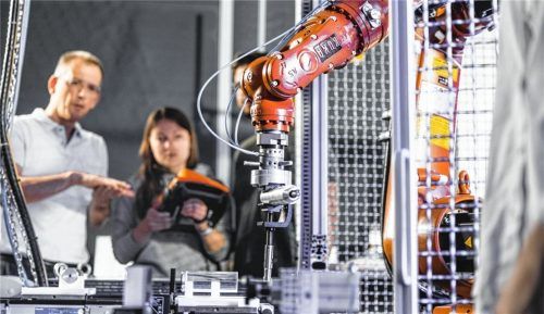 Studierende arbeiten an der automatisierten Werkstückpositionierung mit einem Industrieroboter im Labor Montageautomatisierung und Robotik von Professor Christian Meierlohr (links). Foto Spreadfilms