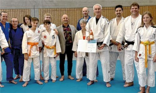 Klaus Gallin (Vierter von rechts) präsentiert in der Runde mit Judoka aus Großkaro undJudo-Bezirksvorsitzendem Denis Weisser (Siebter von rechts) stolz seine Urkunde. Foto re