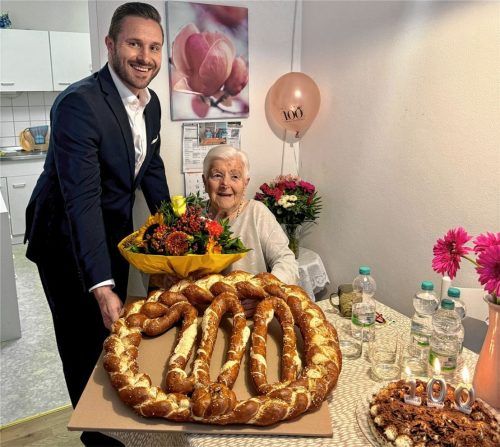 Besuch von Rosenheims Zweiten Bürgermeister, Daniel Artmann: Christa Macha erhält Blumen und eine riesige Geburtstags-Brezel. Foto Renate Kasprzyk