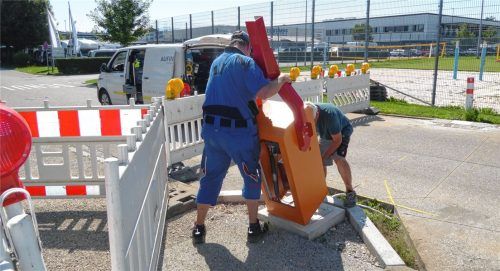 Zwei Männer montieren die Schrankenanlage an der Zufahrt des Parkplatzes der Pauline-Thoma-Schule. Foto Riediger