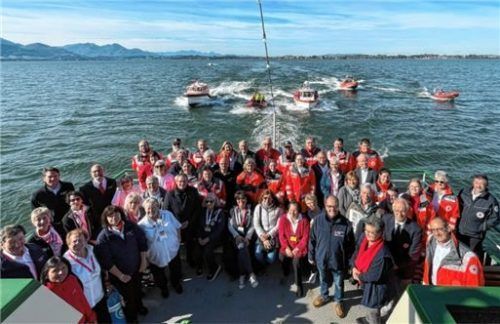 Die 50 engagierten BRK-Helfer versammeln sich zu einem Gruppenbild. Im Hintergrund begleiten die aktiven Mitglieder der Wasserwacht die „Edeltraud“ der Chiemsee-Schifffahrt Ludwig Feßler. Foto BRK
