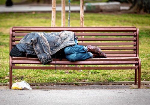 Ein Obdachloser schläft auf einer Bank im Park. Foto istock
