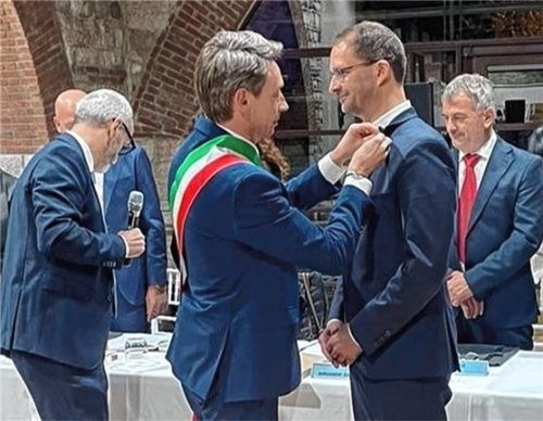 Lazises Bürgermeister Damiano Bergamini heftet Oberbürgermeister Andreas März die Ehrenbürgernadel ans Revers.

Foto Stadt Rosenheim