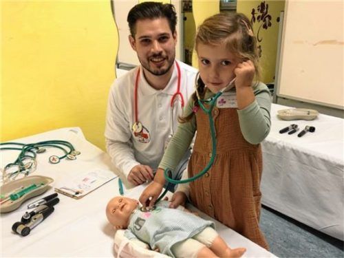 Nico Hanny zeigt einem Mädchen bei ihrer Puppe, wie man mit einem Stethoskop das Herz abhört.