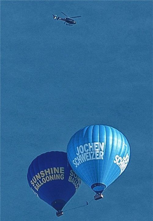 Bei dem Spektakel am Rosenheimer Himmel hat es sich offenbar um einen Slackline-Weltrekordversuch gehandelt. Auf dem Seil zwischen den Ballons balanciert ein Mensch.

Foto Giesler