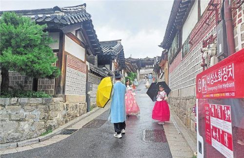 Beliebtes Fotomotiv: Touristen posieren vor den Häusern (gr. Foto). Lee Jun-hee (l.) und ihre Kollegin weisen Touristen darauf hin, wie sie sich in Bukchon verhalten sollen (Foto li.). Schilder ermahnen die Besucher, möglichst leise zu sein (Foto o.).