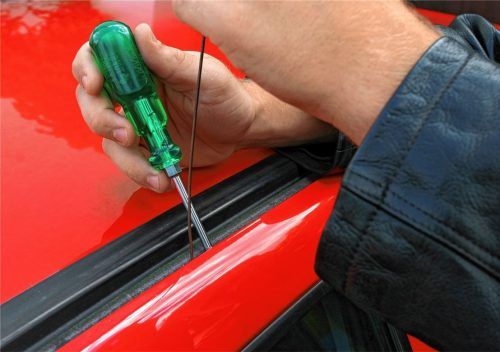 Ein Mann versucht, ein Auto aufzubrechen (Symbolfoto): In Bruckmühl ist ein Täter in mehr als 20 Fahrzeuge eingedrungen, um dort Geld und Wertsachen zu stehlen. Einige Autobesitzer hatten es ihm aber recht leicht gemacht. Foto dpA