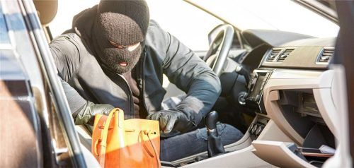 Ein Dieb durchsucht eine Handtasche, die er in einem unverschlossenen Auto gefunden hat (Symbolfoto). Foto Imago/Zoonar.com/Robert Kneschke