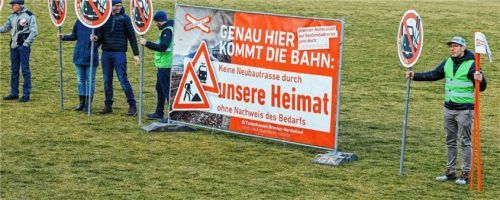 Gegner der geplanten Bahntrasse stehen mit Schildern auf einem Sportplatz, welcher der Strecke weichen müsste.Foto DPA