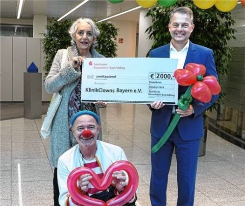 Karl Göpfert, Vorstandsvorsitzender der Sparkasse Rosenheim-Bad Aibling (rechts), bei der symbolischen Spendenübergabe mit Andrea Andrade von den „KlinikClowns“ Bayern zusammen mit Clown Lupino.Foto re