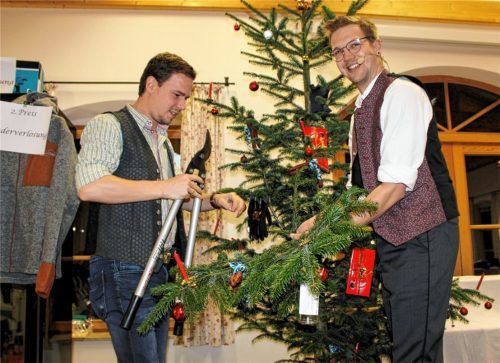 Ran mit der Heckenschere: Thomas Kirchberger (links), Vorsitzender der Freiwilligen Feuerwehr Litzldorf, mit dem ersteigerten Ast vom Christbaumgiebel. Auktionator Simon Wallner hat sichtlich seinen Spaß. Foto Strim