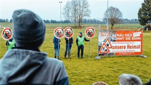 Gegner der geplanten Bahntrasse stehen mit Schildern auf einem Sportplatz, welcher der Strecke weichen müsste. Die Auswirkungen des Neubaus wären weitreichend. Foto dpa