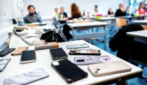 Zahlreiche Smartphones liegen auf einem Schulpult: Im Bad Aiblinger Gymnasium sind Handys im Schulalltag nicht mehr gern gesehen. Eine neue Regelung schränkt die Benutzung von Smartphones an der Schule ein. Foto dpa
