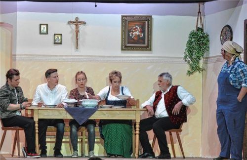 Dicke Luft am Familientisch in der Stube: (von links) Sohn Josef (Manuel Finsterwald), Sohn Sebastian (Roman Wurmannstetter), Tochter Theresa (Sandra Kirschner), Bäuerin Berta (Angelika Schmid), Bauer Benno (Rupert Huber) und (rechts, stehend) Magd Maria (Maria Scalise). Foto  Theatergemeinschaft Amerang