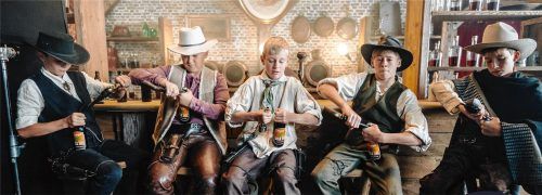 Die „Spezi-Suchtis“ (von links) Flori, Korbi, Louis, Finn und Johannes versuchen in einer Drehpause an der Bar des Saloons Spezi-Flaschen mit Pistolen zu öffnen. Foto Flötzinger Privatbrauerei Franz Steegmüller